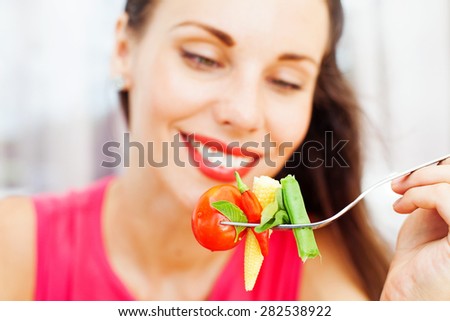 closeup of woman eating a healthy vegetarian salad (focus on salad)