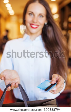 Shop assistant handing a card to a customer (soft focus on a card)