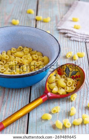 dry pasta on a wooden table in an iron bowl with a wooden spoon