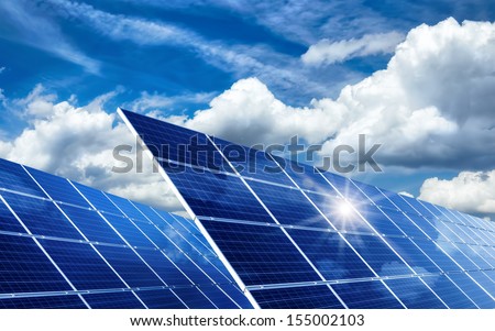 Two large solar panels under the blue sky with lively clouds, reflecting the sun