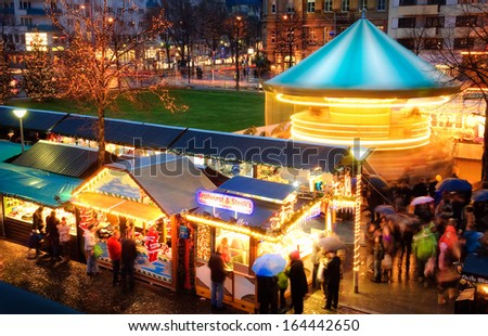 Illuminated Christmas fair with loads of movement, people in motion, no logos or faces