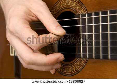 Close-up of a spanish guitar being played using a plectrum