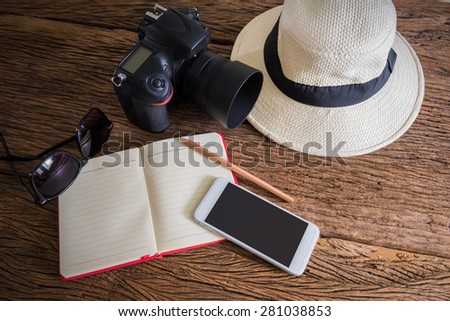 travel, summer vacation, tourism and objects concept. close up of hat, notebook, pencil, camera, smartphone and sunglasses on wooden table. Photo retro style