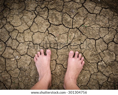 Barefoot standing on dry and cracked ground background and texture