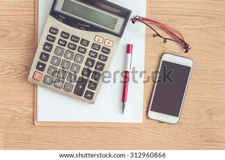 clipboard with a pen and  calculator, eyeglasses on office table