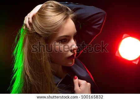 Beautiful girl posing in front of shining colored creative lighting background