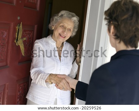 Smiling senior woman greeting visitor at the front door
