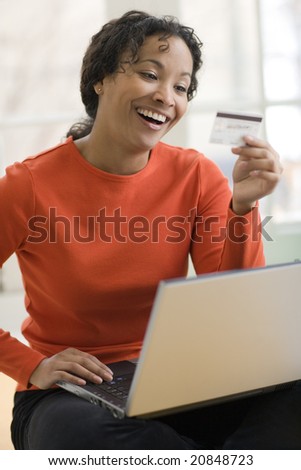 Smiling African American woman shopping on-line with credit card and laptop computer