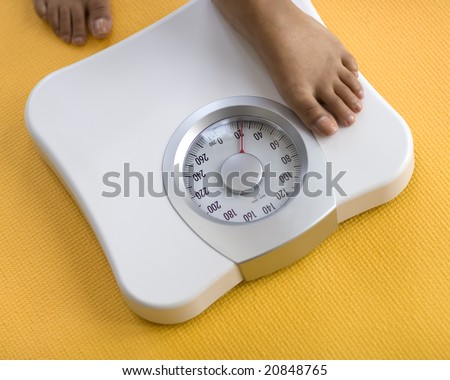 African American Woman weighing herself on a bathroom scale