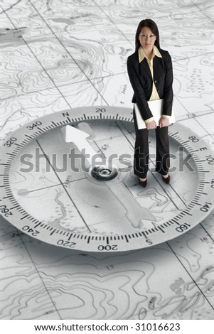 Pretty Asian businesswoman with laptop computer standing on a map with a compass background