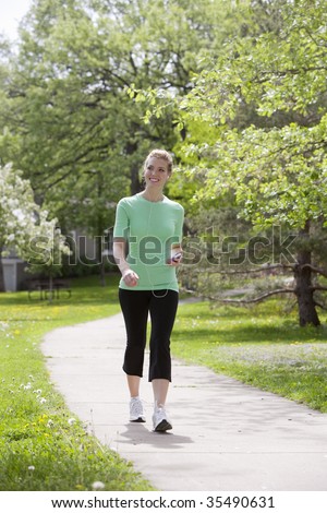 Pretty woman walking in the neighborhood listening to music on her MP3 player
