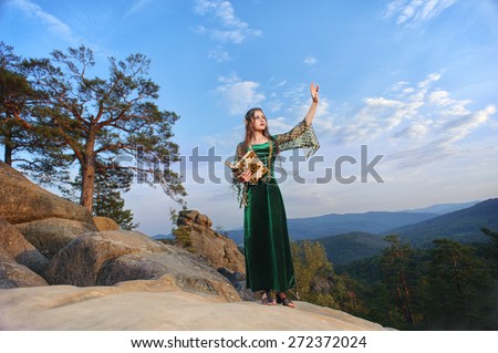 Elf woman in the mountains against the sky waving hands