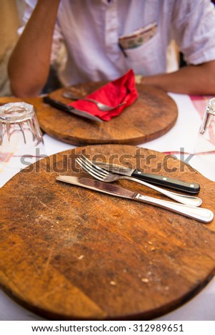 Photo of the cutlery and wooden boards left after a pizza meal in italian restaurant