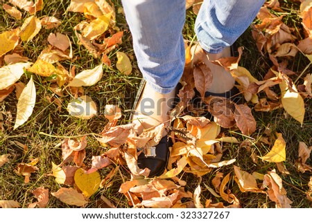 Female feet among the yellow fallen leaves and green grass