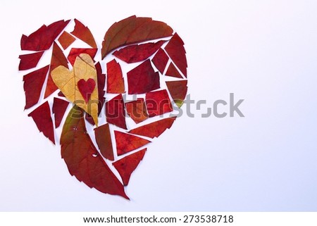 Autumn leaves cut into pieces and arranged in a heart pattern with two smaller hearts all on a white background