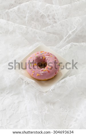 A yummy doughnut on a white background. This sweet photo would work well for bakeries, restaurants, food magazines, children\'s food, advertisements, greeting cards, or many other ideas and concepts.