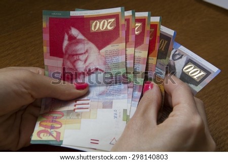 Money in hands.Woman holding a bunch of Israeli New Sheqel banknotes in her hands.