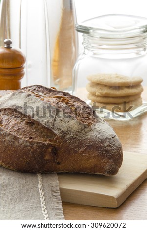 Freash Tradition bread loaf on the kitchen table with cakes jar and kitchen utensils