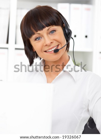 Beautiful secretary with headset is working in office