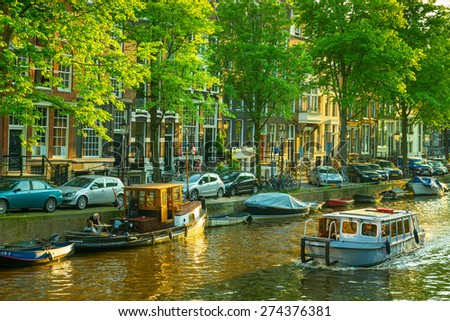 Amsterdam - May 23, 2012: Unknown people in a boat on an Amsterdam canal. Spring in Amsterdam.