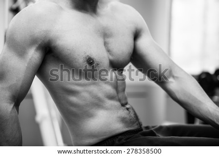 Muscular power athletic male bodybuilder upper body in fitness center. Back and white photo