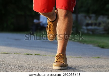 man running legs in park, leather shoes, red shorts