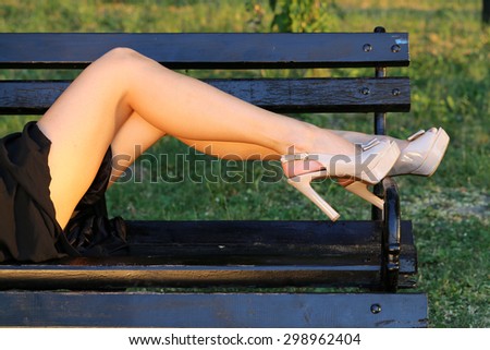 beautiful legs in shoes of a woman lying in park on bench