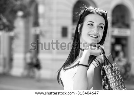 Happy young fashion woman with shopping bags on a city street, black and white photography