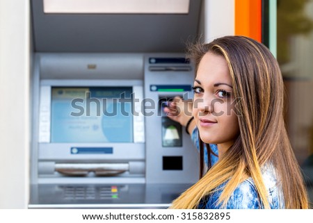 young woman inserting credit card at ATM