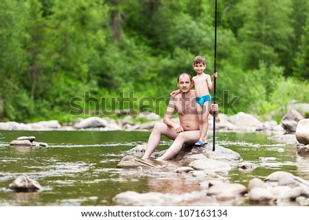 Father and son on a mountain river with a fishing rod