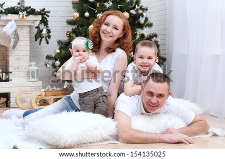 Happy young family at the Christmas tree with a fireplace