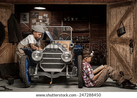 Two boys standing at the mechanic with tools retro car near the garage