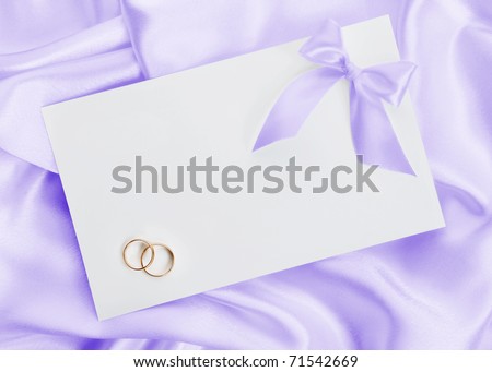 The wedding invitation with wedding rings on a violet background