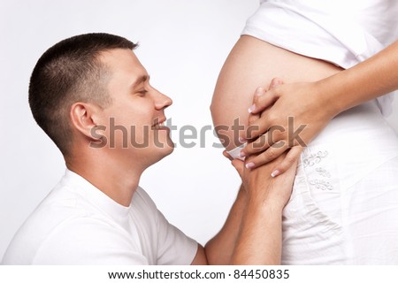 Happy pregnant woman with the husband in studio on grey
