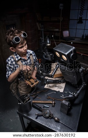 Young boy mechanic starts the robot in his workshop