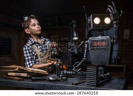 Young boy mechanic starts the robot in his workshop