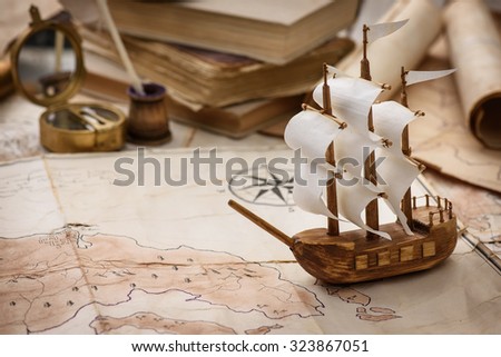 Vintage still-life of old maps, a model of the ship, magnifying glass, old letters on the background of vintage cards