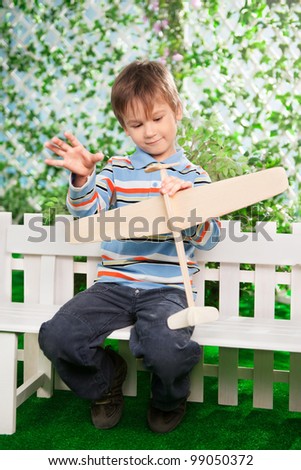 Boy play with plane at a fence in a garden