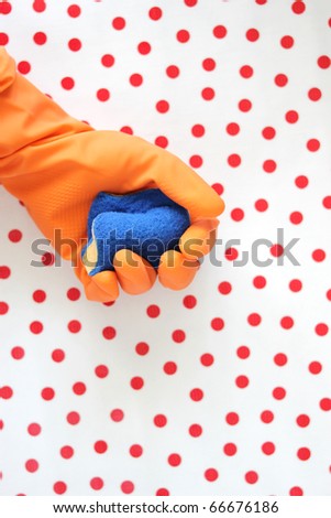Clean up your house - colorful rubber gloves with sponge over tablecloth with polka dots