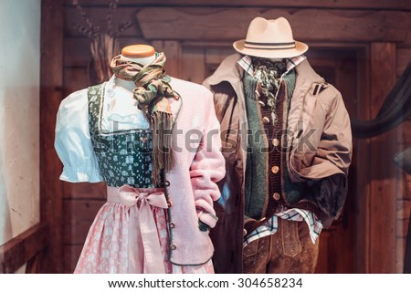 National styled costumes for female and male exposed in a show case of a shop in Salzburg, Austria. A dress and a shirt with jacket of pastel soft colors combination of pink, green and brown.
