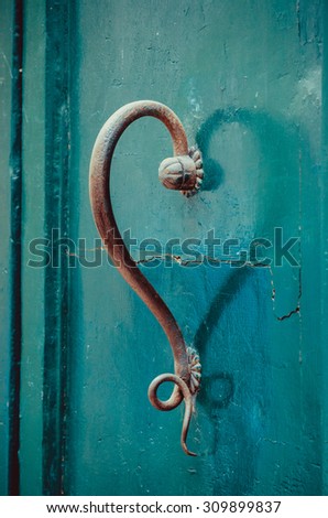 Door handle beautifully shaped and creating the form of a heart with its shadow. Emerald green door with vintage handle.