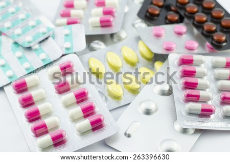 Capsules and pills packed on white background