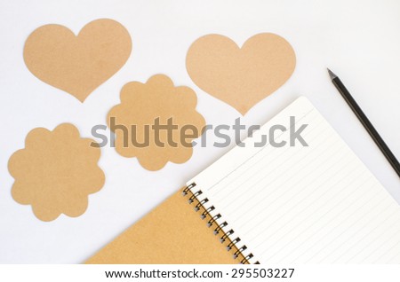 Notebook from recycle paper and black pencil with group of different brown tag on white background - heart and flower tag