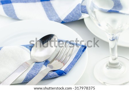 Spoon and fork at blue napkin on white plate - dinner time
