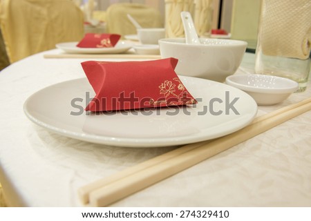 Table setting on a round table of chinese style formal dining.   Red box door gift is placed on the plate.  Text can be insert on the red box.