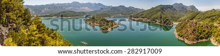 Turkey . Panorama . Huge deep lake in the mountains . Rocky coast with pine trees growing on them . Clean water, allowing breeding trout.
