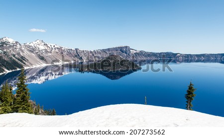 Clear blue water of Crater Lake National Park in Oregon during early spring with some snow left from winter. Wizard Island in the distance.