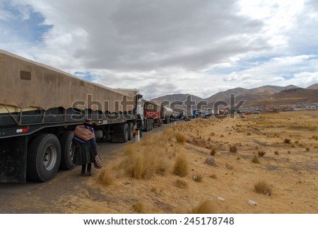 AUGUST 16, 2006 - PUKARA, PERU: Truck Traffic along the road as people walk beside the road with the mountains the background.