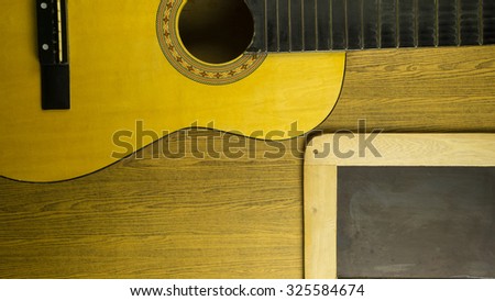 Close up of an acoustic guitar without  guitar strings on a wooden floor,and slate board, shot from above