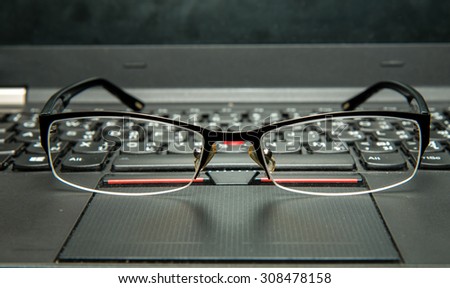 Close up the glasses on laptop computer. Dust on glasses and laptop from office working.(Selective focus on center of glasses and shallow depth of field)